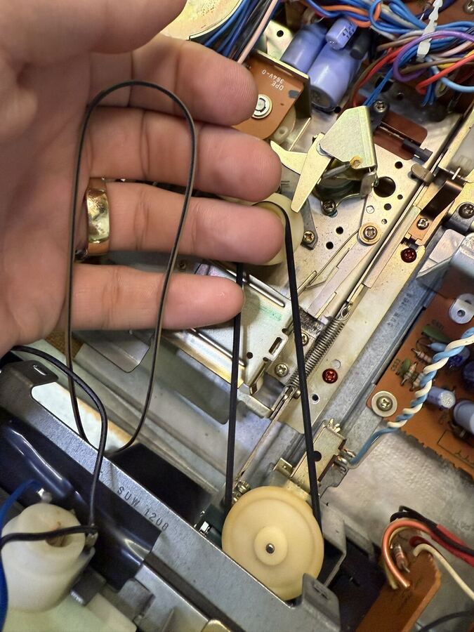 Worn rubber belts held up beside the VCR deck they came from