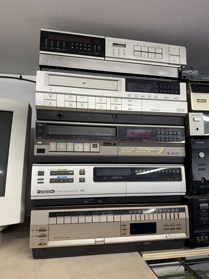 Stack of five 1980s VCRs waiting for service